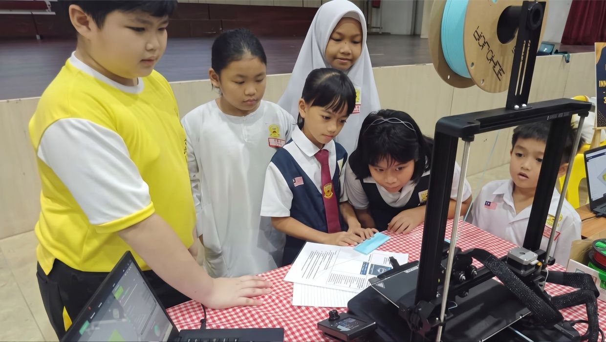 Students eagerly observing how a 3D printer machine operates.