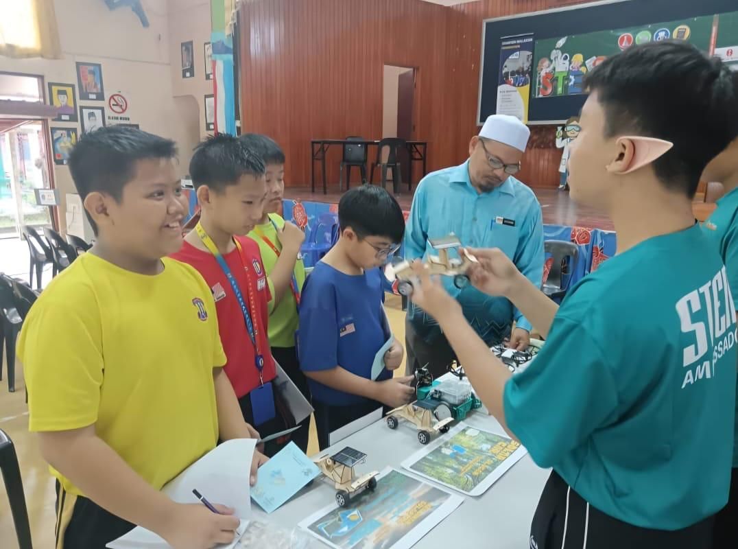 Students working together at interactive educational stations during a STEM workshop. Students engaging with their peers by explaining and demonstrating their projects.